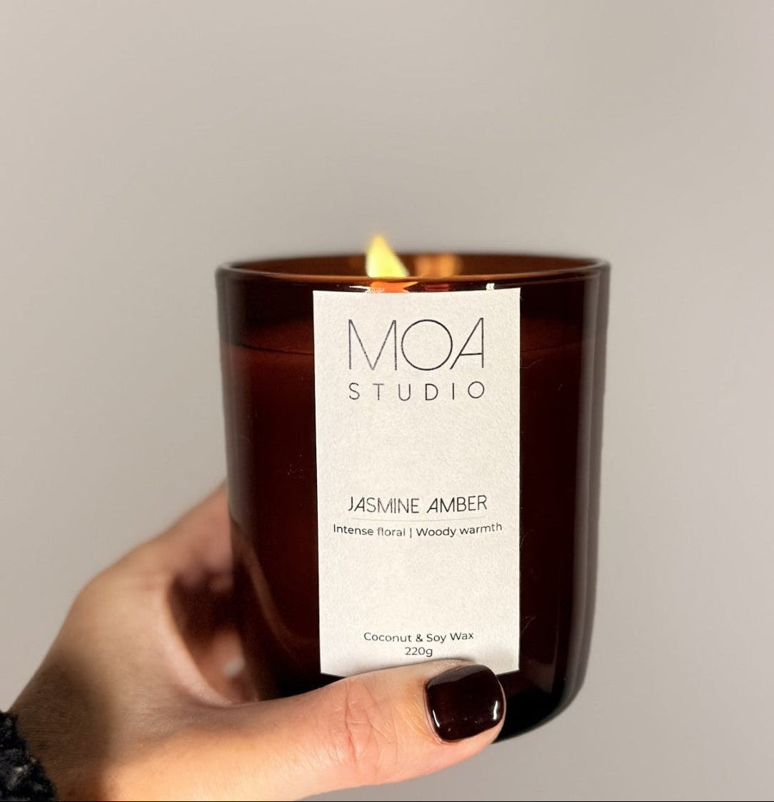 Hand holding a MOA Studio candle with a plain background
